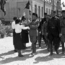 Mussolini, accompagnato da Baistrocchi e da autorità locali, riceve un omaggio floreale da una giovane fascista
