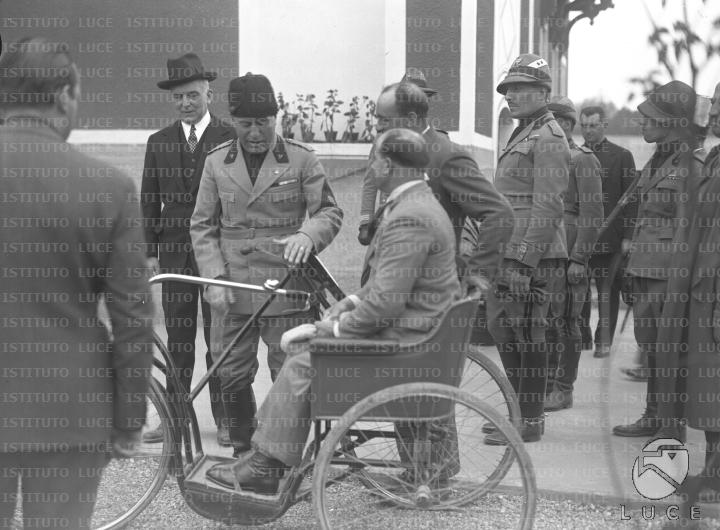 Mussolini si intrattiene con un invalido su triciclo all'esterno di un ...