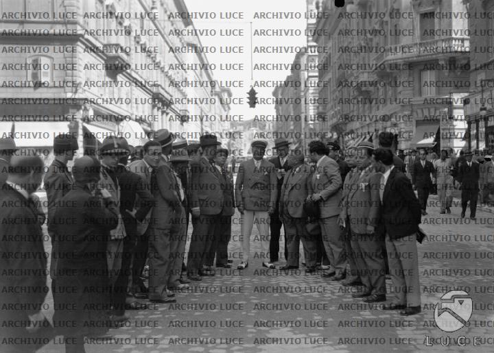 Mussolini si intrattiene con un gruppo di personalità in mezzo a via ...