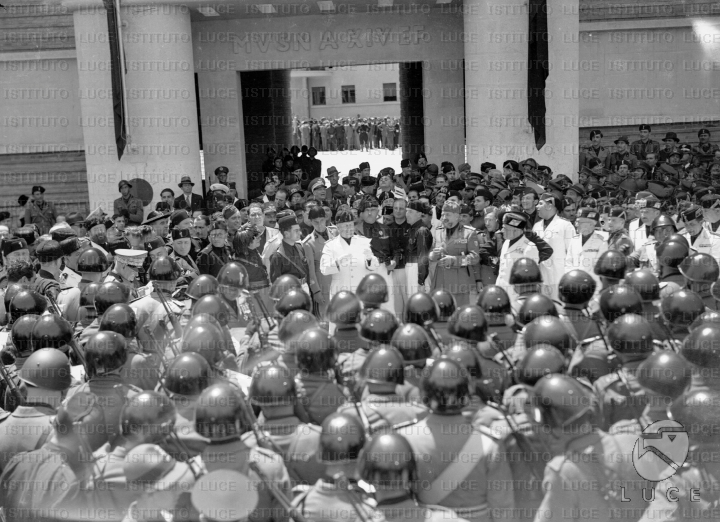 Mussolini al centro di una folla di militi e autorità fasciste durante ...