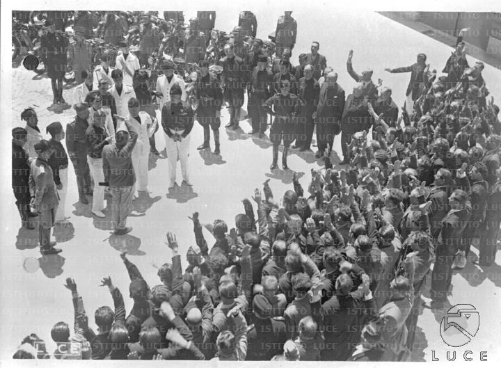 Una folla di uomini rivolge il saluto fascista a Mussolini durante la ...