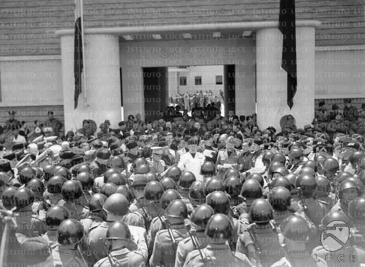 Mussolini al centro di una folla di militi e autorità fasciste durante ...