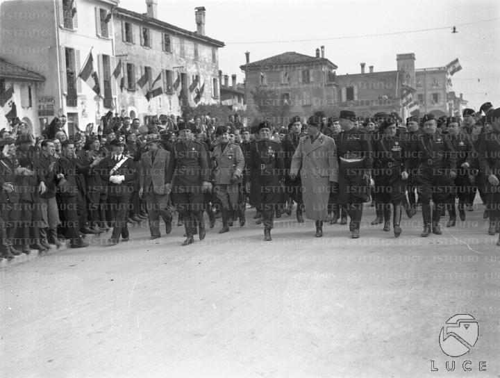 Mussolini, accompagnato da un folto gruppo di gerarchi, percorre le ...