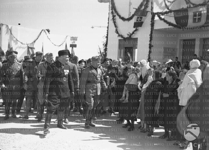 Mussolini, accompagnato da un folto gruppo di autorità fra cui il ...