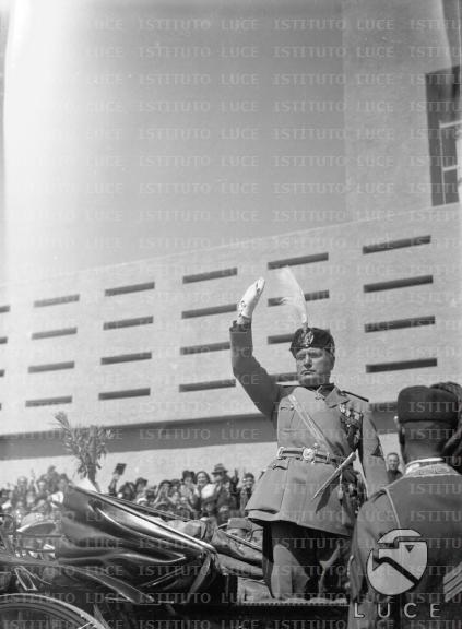 Mussolini, ritto sulla carrozza, fa il saluto fascista rivolto alla ...