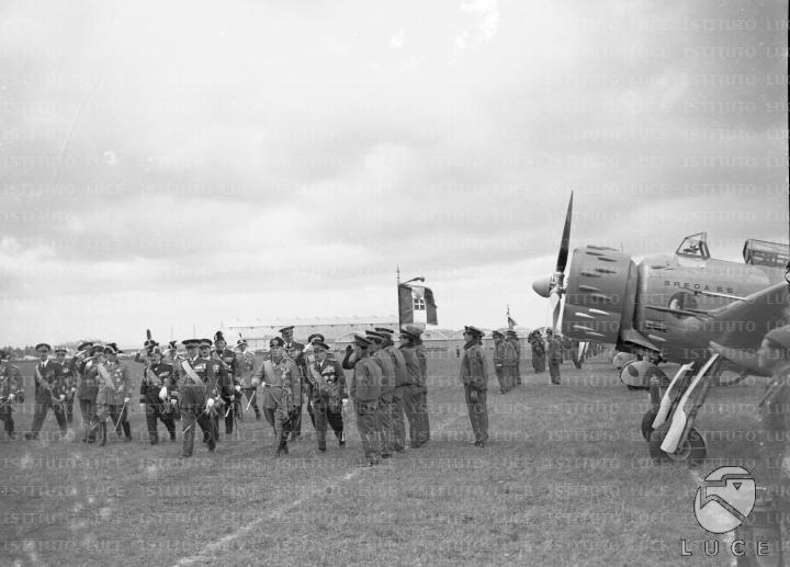 Mussolini, accompagnato da un folto gruppo di autorità militari, passa ...
