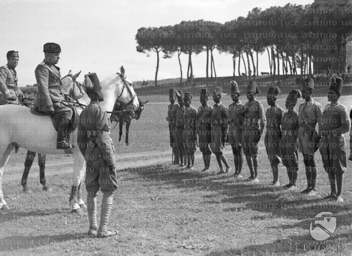 Mussolini, in sella a un cavallo bianco, si intrattiene con una squadra ...