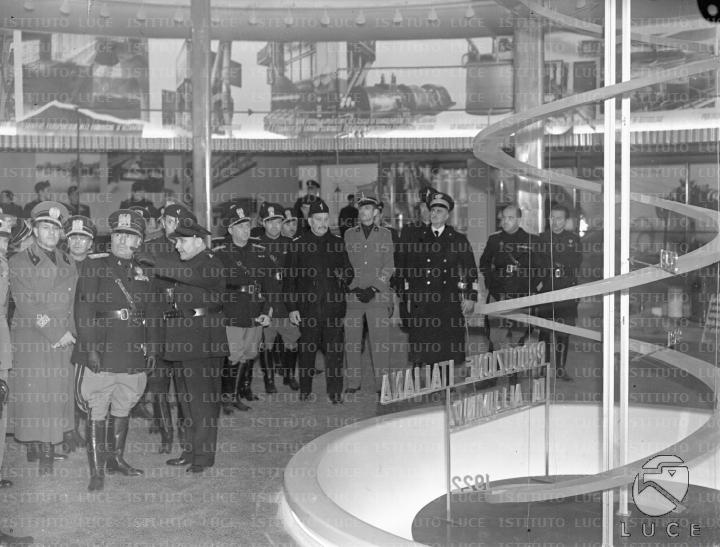 Mussolini, guidato da un esperto, si sofferma con un gruppo di gerarchi ...