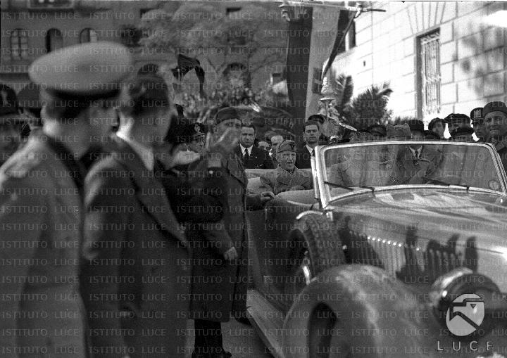 Il re sull'automobile viene salutato da autorità fasciste locali, al