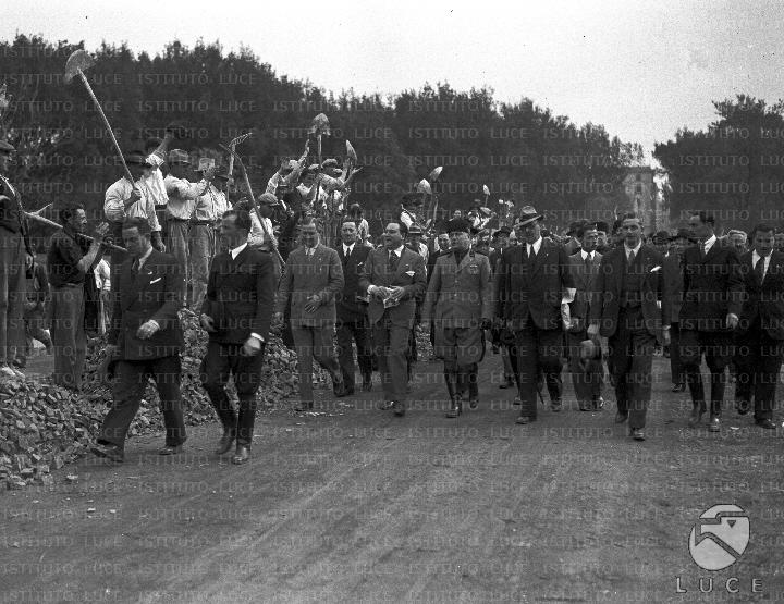Gli operai salutano Mussolini e il gruppo di personalità che lo ...