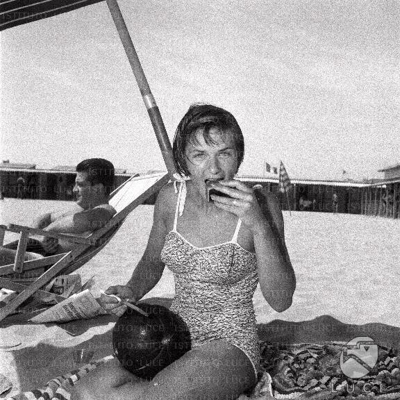 Mariolina Bovo in spiaggia, mangia un frutto esotico sotto l'ombrellone