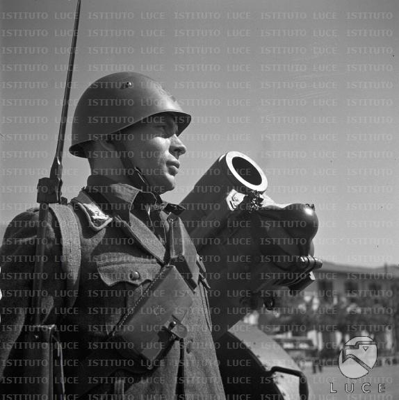 Un soldato con fucile e sull'attenti, a lato si vede la bocca