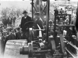 Mussolini in piedi su un trattore con un lavorator ...