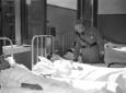Mussolini visita un ragazzo sul letto; campo medio