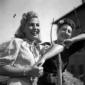 Ragazza sorridente posa appoggiata ad un forcone;  ...