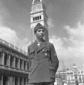 Un ragazzo militare posa davanti al campanile; pia ...