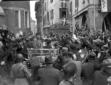 La folla circonda Mussolini, in piedi a bordo di u ...