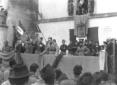 Comizio fascista con spettatori disposti su tre la ...