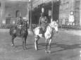 Due uomini in uniforme, a cavallo, al centro di Pi ...