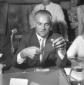 Alberto Moravia ha una scheda in mano, seduto al t ...