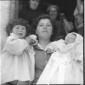 Una donna con due piccole bambine in braccio; pian ...