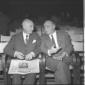 Due uomini seduti  in platea che discutono. Totale